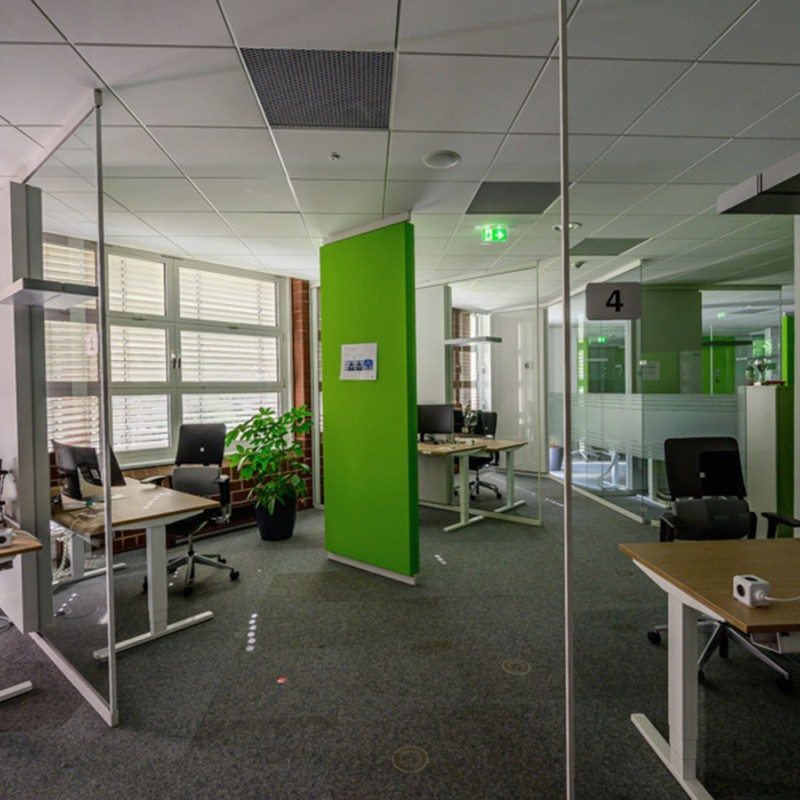 Großer Büroraum mit Schreibtischen und Abtrennungen aus Glas