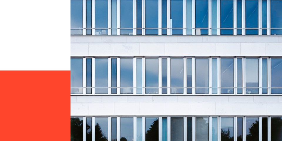 Ausschnitt Gebäudefassade mit viel Glas neben Farbflächen